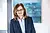 Mitarbeiterin Frau Dahl in einem modernen Büro, lächelnd vor abstrakter Kunst im Hintergrund.