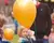 Ein gelber Luftballon, im Hintergrund Kinder und Erwachsene auf einem Fest.