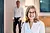 Mitarbeiterin Frau Steinbach mit Brille lächelt in einem modernen Büroumfeld, während eine verschwommene Person im Hintergrund steht. Mitarbeiterin Frau Steinbach mit Brille lächelt in einem modernen Büroumfeld, während eine verschwommene Person im Hintergrund steht.