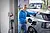 Mann in blauer Jacke lädt sein Elektroauto an einer Ladestation in einer modernen Garagenumgebung auf.
