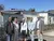 Gruppe von fünf Personen vor einem Gebäude mit Solarpanelen, bei sonnigem Wetter.