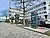 Moderne Ladestationen für Elektrofahrzeuge auf einem Parkplatz vor einem modernen Bürogebäude, umgeben von Bäumen und Autos.