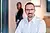 Professionelles Porträt des Mitarbeiters Herr Hausmann mit Brille in einem modernen Büro, eine Frau im Hintergrund leicht unscharf. Professionelles Porträt des Mitarbeiters Herr Hausmann mit Brille in einem modernen Büro, eine Frau im Hintergrund leicht unscharf.